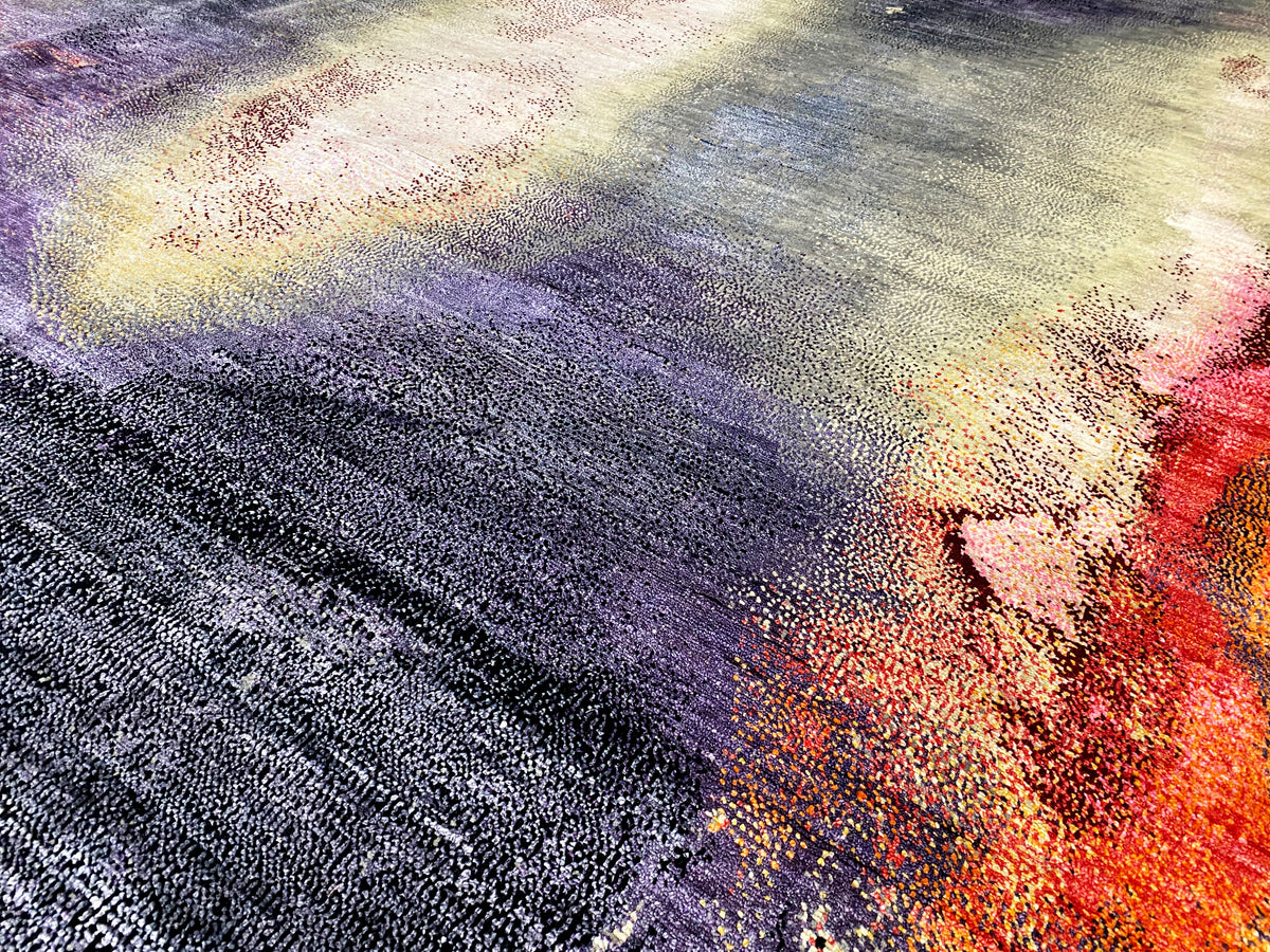Designer rug with an abstract pattern in purple, blue, cream, and orange; high-pile texture.