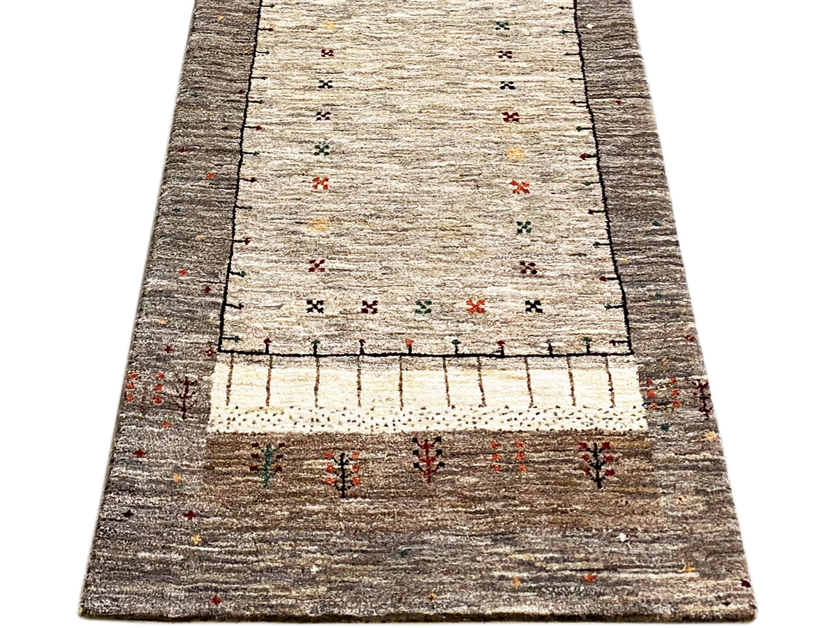 Gabbeh runner in portrait view: light central field, dark border, decorative pattern