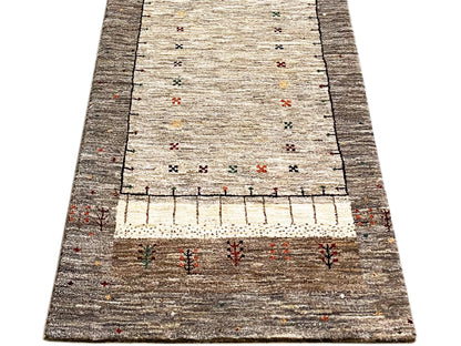 Gabbeh runner in portrait view: light central field, dark border, decorative pattern