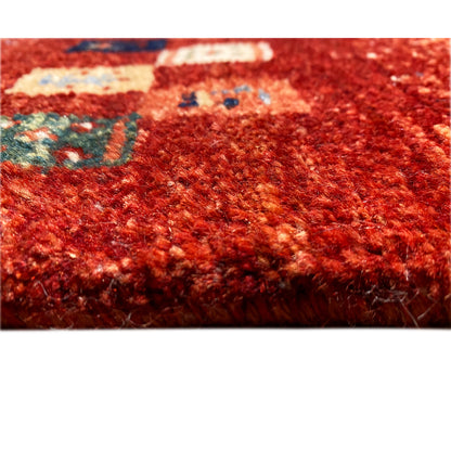 Close-up of a Gabbeh rug: dense red pile with multicolored pattern fragments