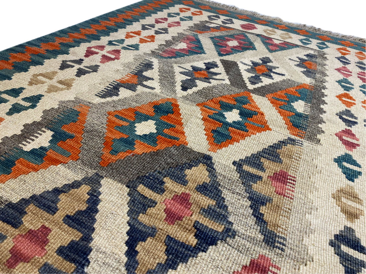 Kilim rug with a cream-colored base and colorful geometric patterns, border with fringes