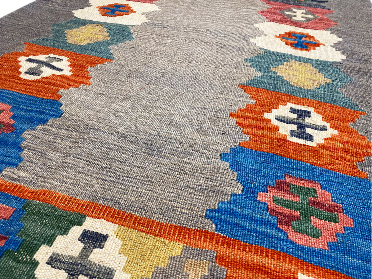 Gray marled kilim rug with a multicolored block pattern along the edge