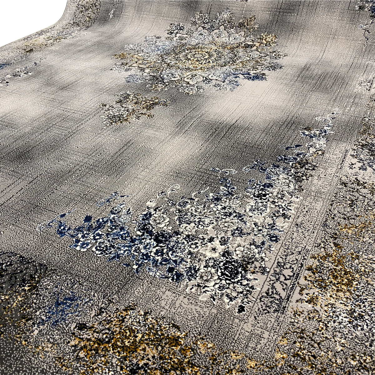 Close-up of a carpet: gray surface with blue and gold floral motifs, fine patterned texture