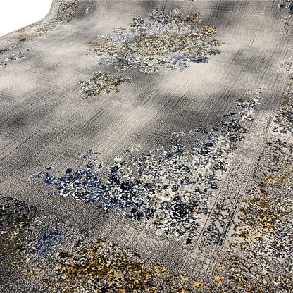 Close-up of a carpet: gray surface with blue and gold floral motifs, fine patterned texture