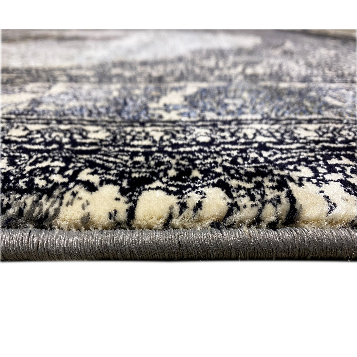Carpet pile in detail: black-and-gray patterned, beige strands and fringes