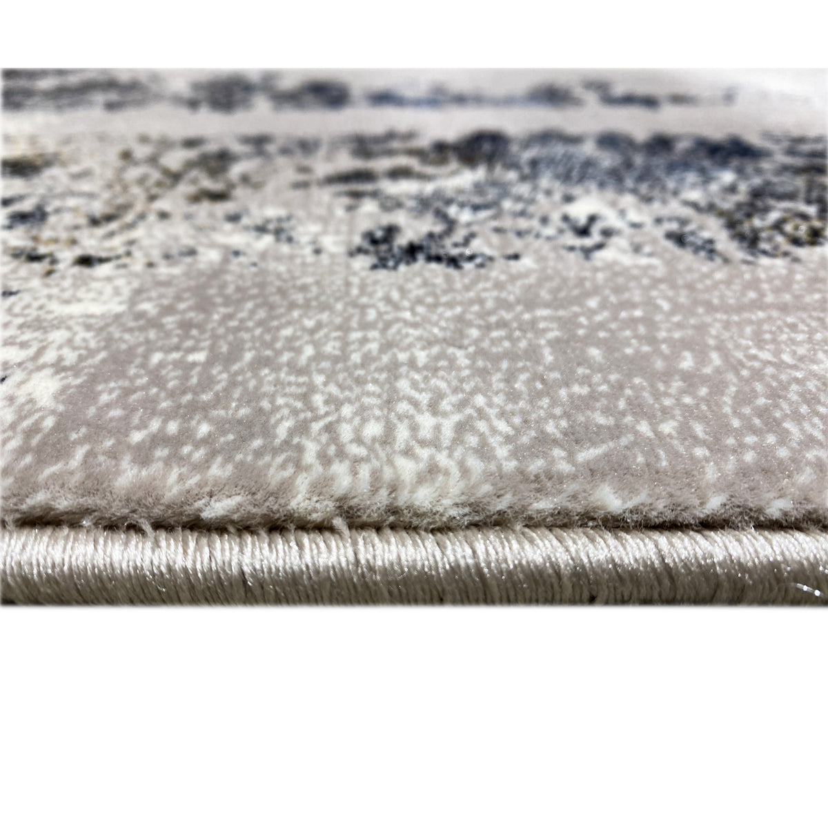 Close-up of a carpet edge with fringes and a blue-and-gold ornamental pattern