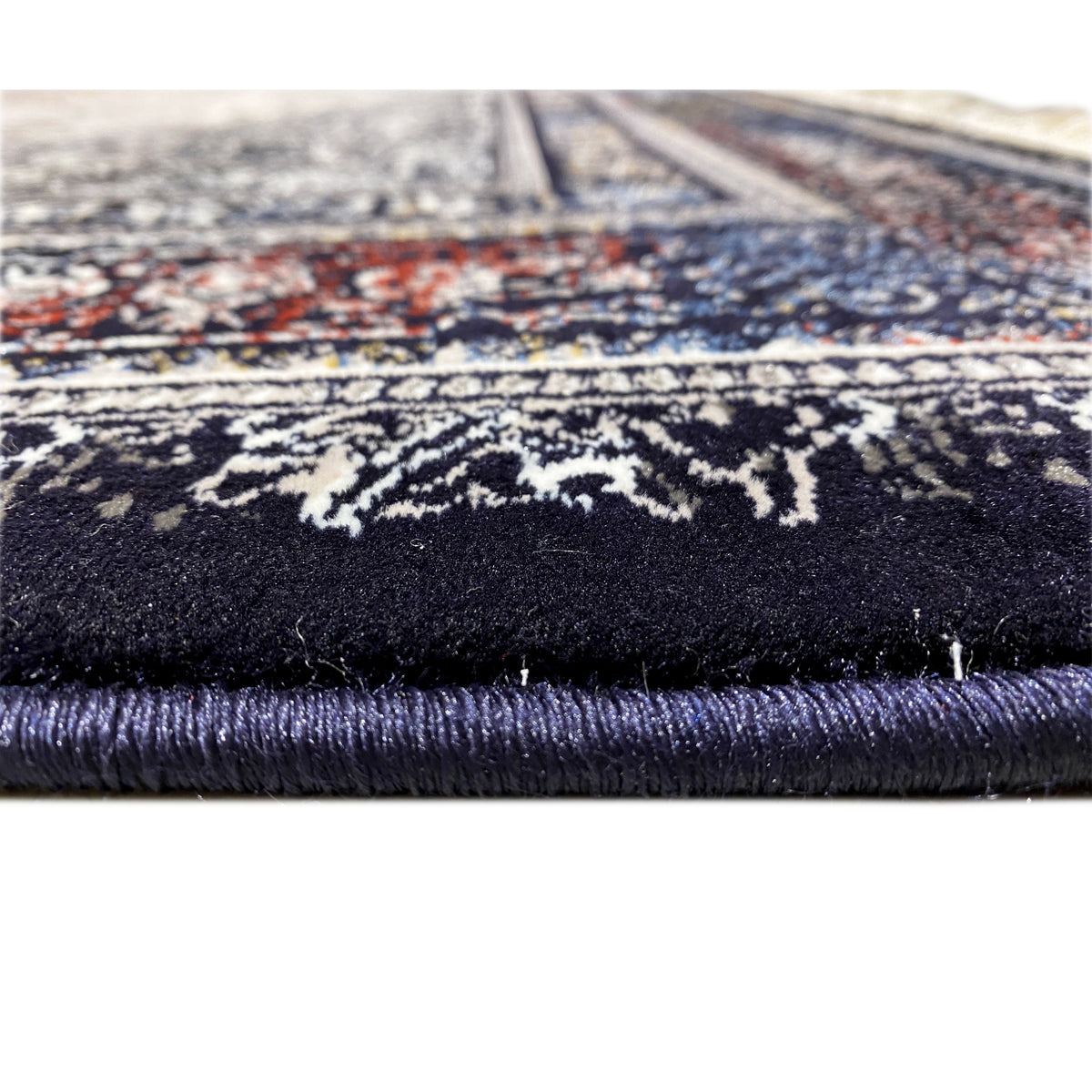 Rug detail at the edge: fringe and dark pile, with an ornamental stripe in gray and blue above