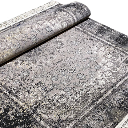 Vintage rug in gray, partially rolled, with a detailed ornamental pattern