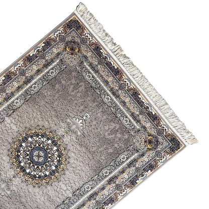 Corner view: anthracite-colored rug with ornamental border, fringe, and gold accent