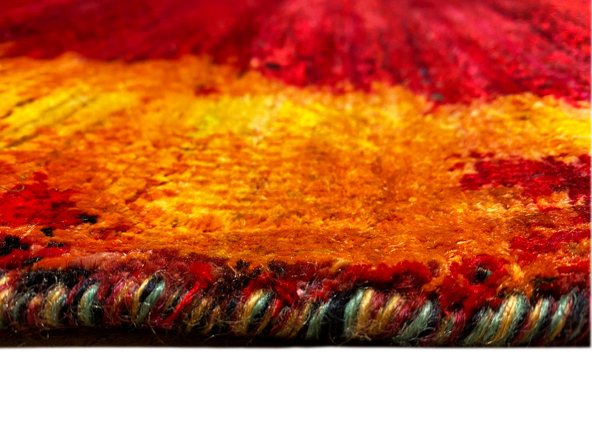 Close-up of designer rug: red and orange pile with yellow gradients, fringed edges