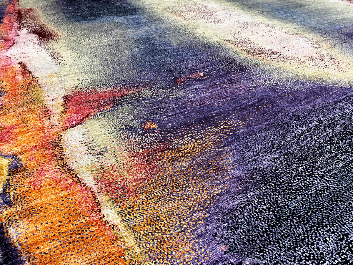 Designer rug close-up with bold orange and purple patches as well as light cream areas.