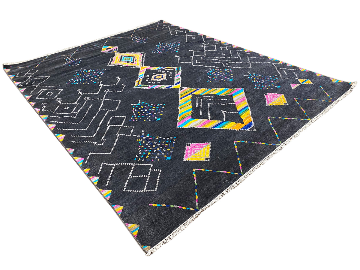 Black designer rug with colorful square and line patterns, photographed at an angle