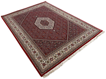 Red Bidjar rug laid flat with a medallion in the center, border, and fringes