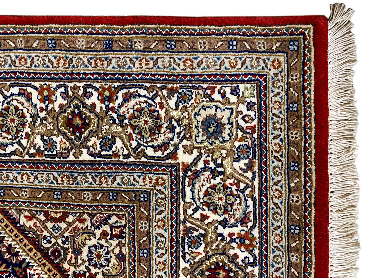Carpet with a red base, white and blue ornaments, and a fringe border along the sides