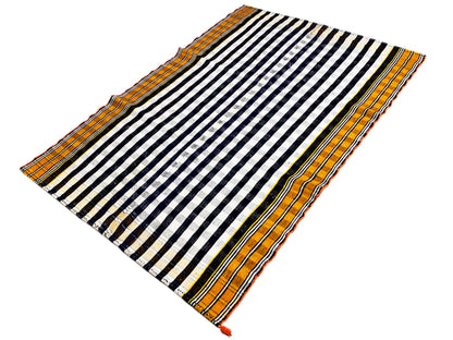 Jajim rug laid at an angle with a black-and-white striped pattern and orange border trim