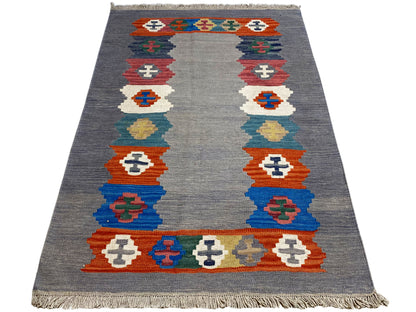 Gray heathered kilim rug with a rectangular border pattern and fringes
