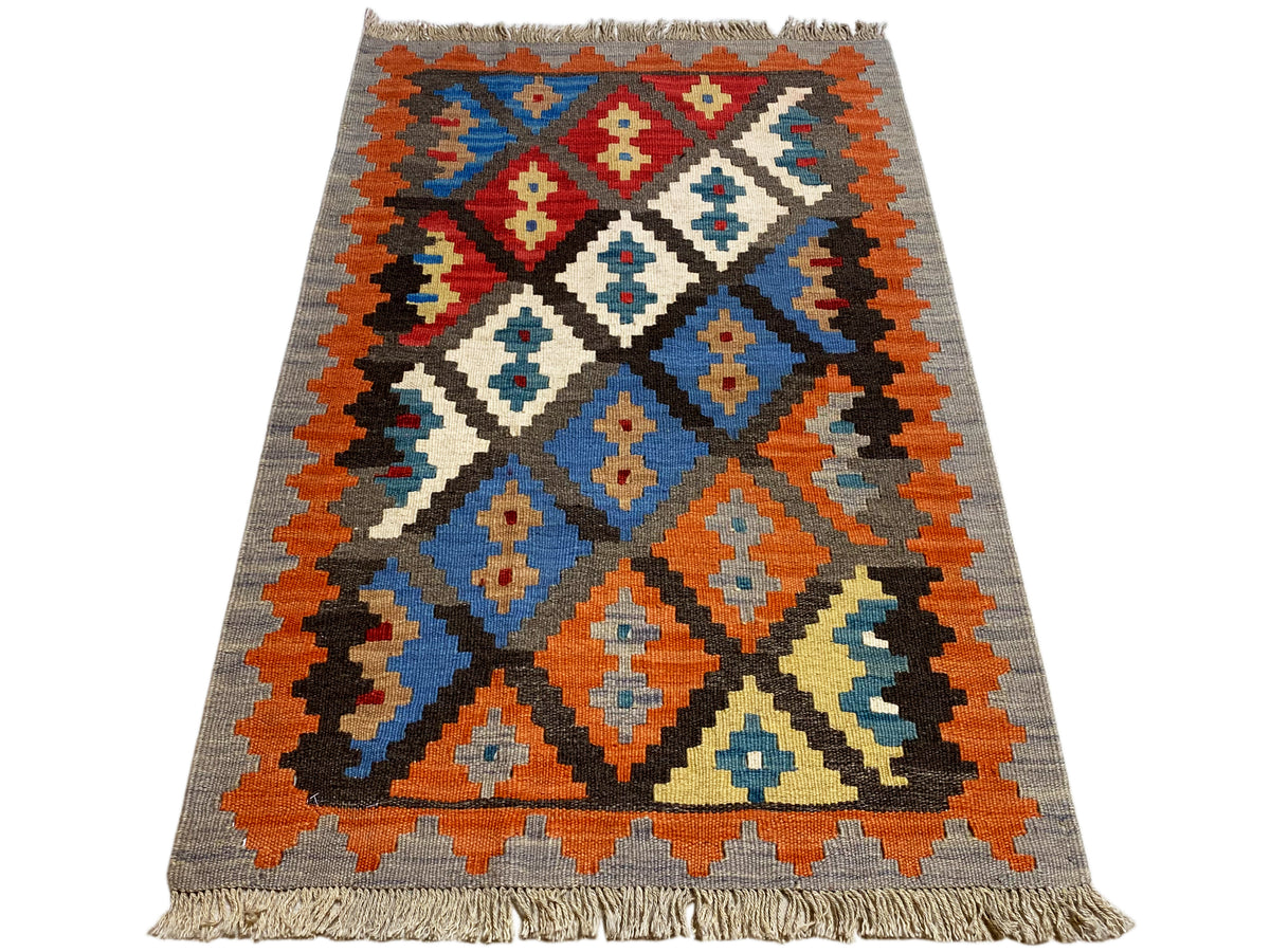 Kilim rug with geometric pattern, gray base, orange, blue and red accents, fringes