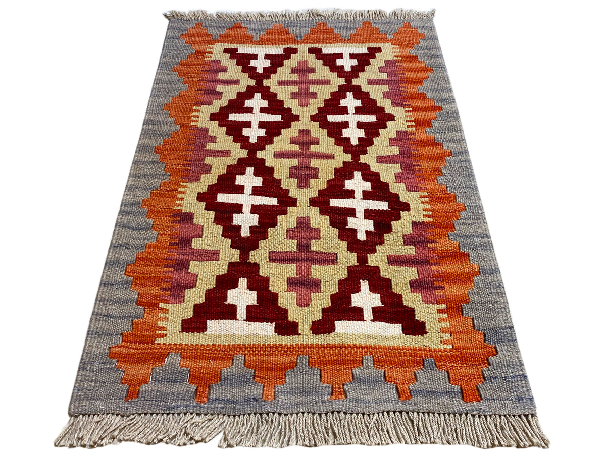 Kilim rug with a geometric pattern in gray, orange, cream, and dark red, fringes
