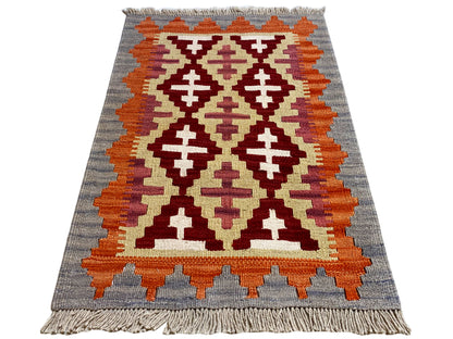 Kilim rug with a geometric pattern in gray, orange, cream, and dark red, fringes