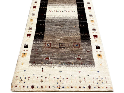 Gabbeh runner with a deep central field, surrounding stripes, and colorful small motifs