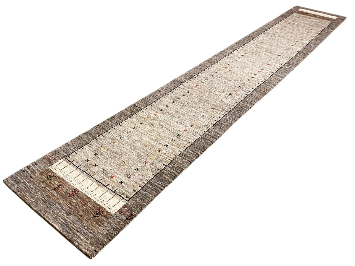 Gabbeh runner at an angle: light beige center with colorful dots, border