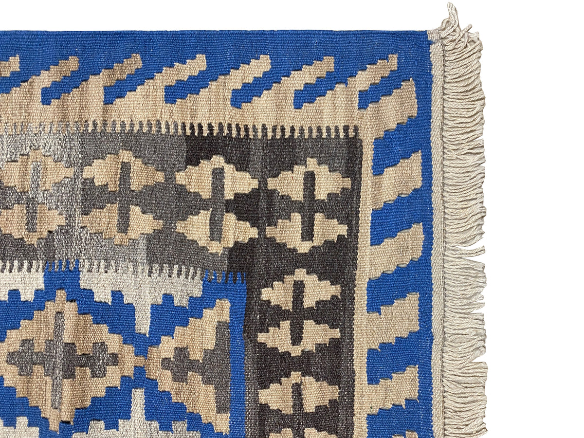 Detailed view: Kilim rug edge with fringe and blue stripe trim, beige inner pattern