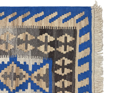 Detailed view: Kilim rug edge with fringe and blue stripe trim, beige inner pattern