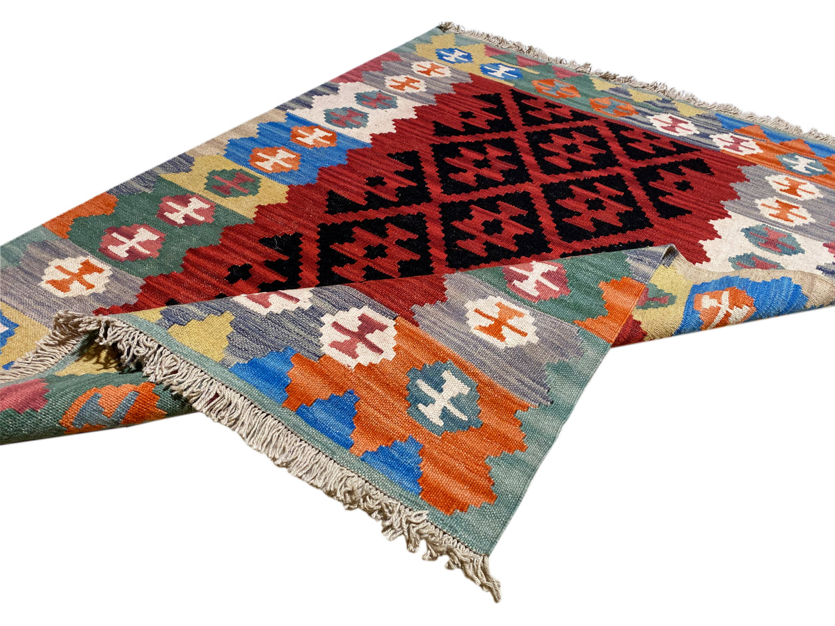 Kilim rug with geometric row patterns and fringe at one corner, multicolored