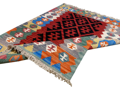 Kilim rug with geometric row patterns and fringe at one corner, multicolored