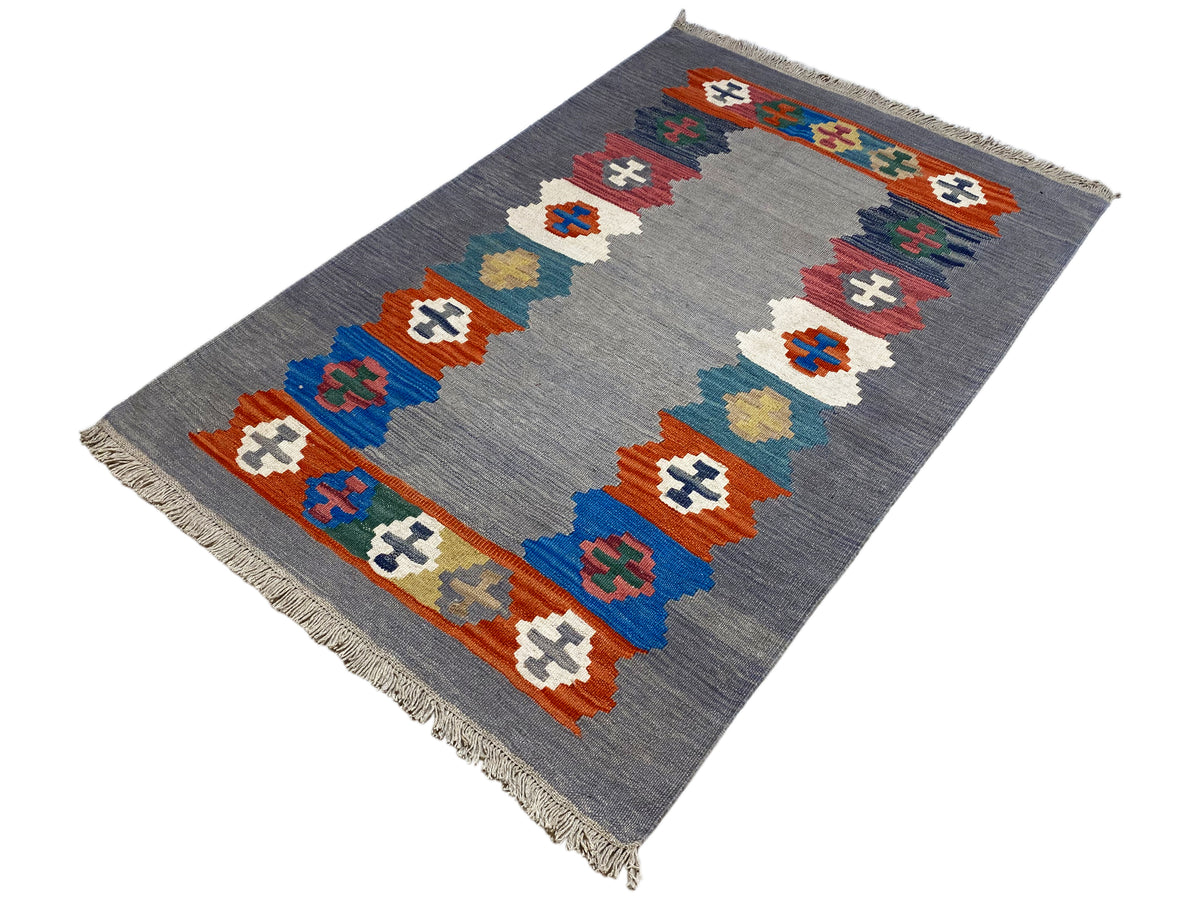 Gray heathered kilim rug with a diagonal border of colorful symbols and fringes