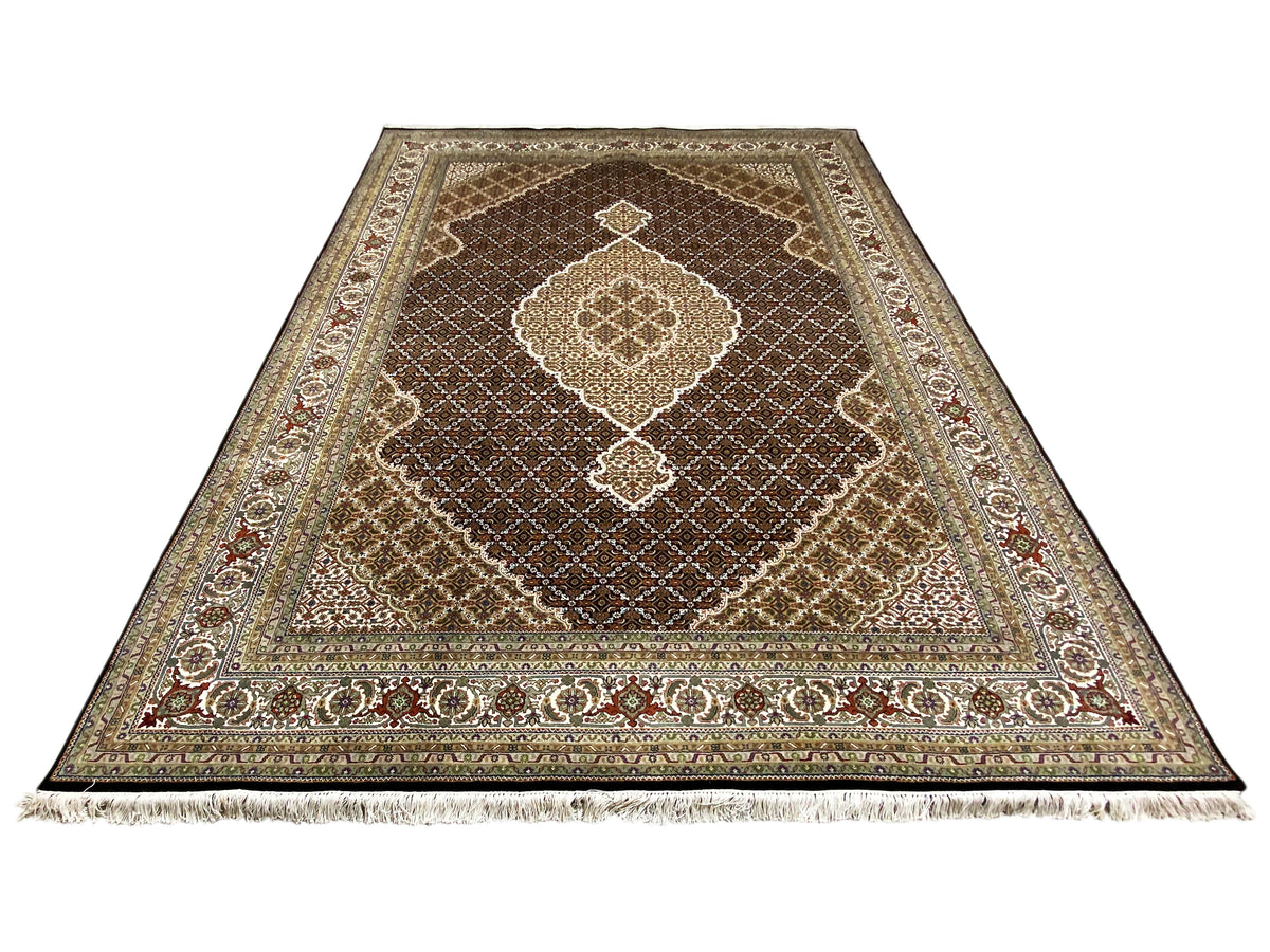 Brown Indo-Tabriz rug with an ornamental medallion, floral border, and fringes.