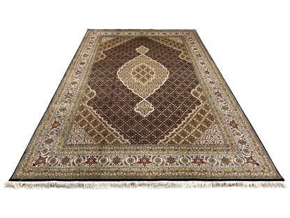 Brown Indo-Tabriz rug with an ornamental medallion, floral border, and fringes.