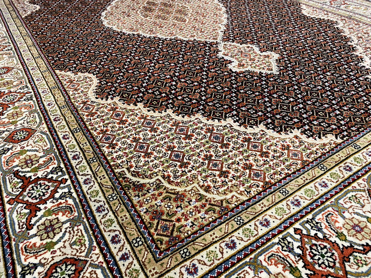 Close-up of a brown Indo-Tabriz rug: border ornaments and a dark floral pattern