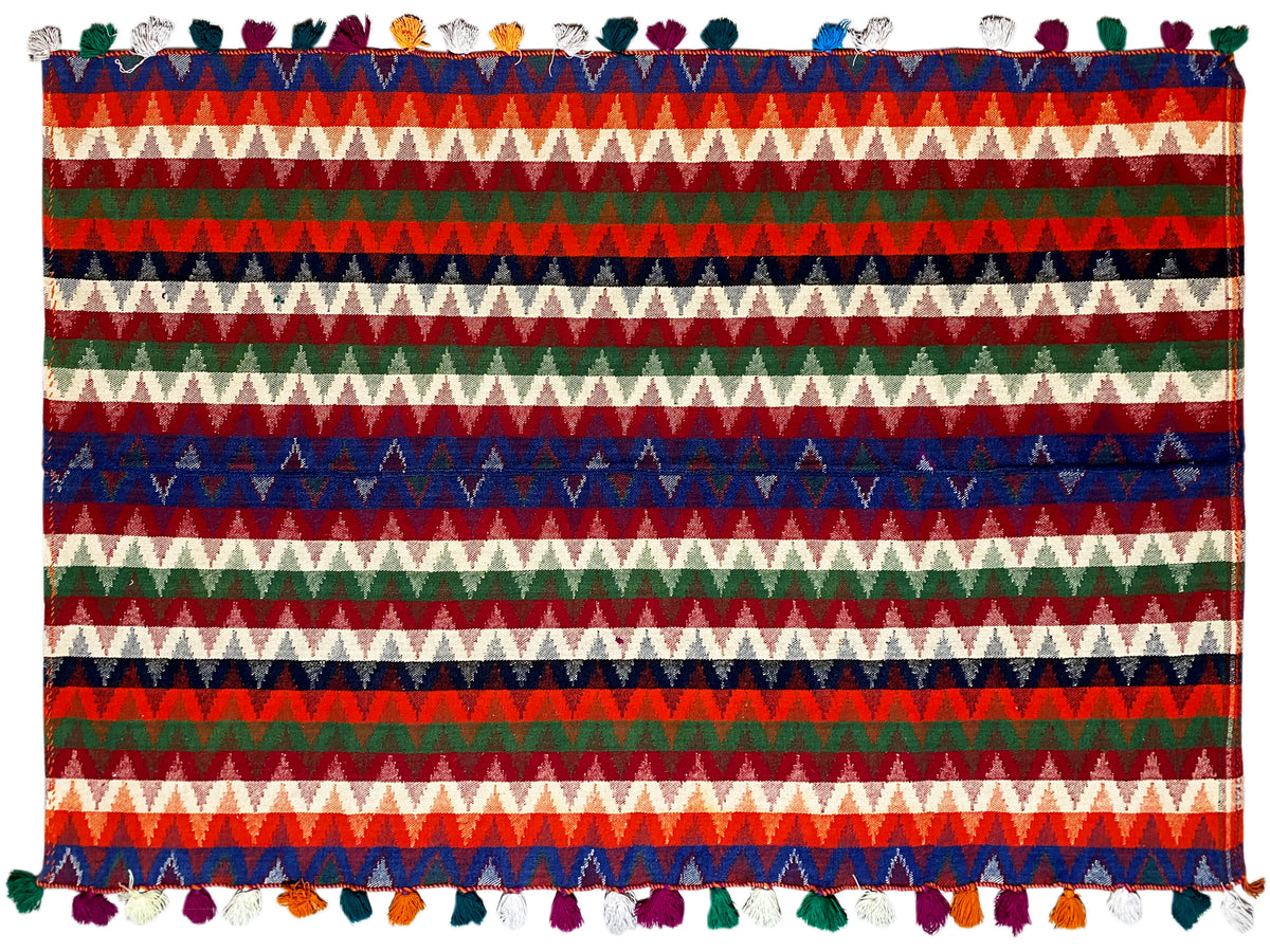 Close-up: rug with a striped pattern in blue, green, and red, with tassels along the edge