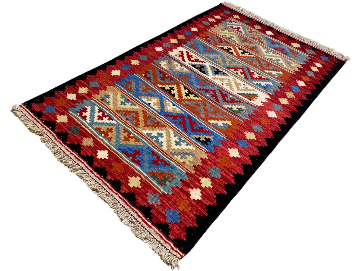 Kilim rug with colorful geometric design in red, blue, and beige, with fringe trim.