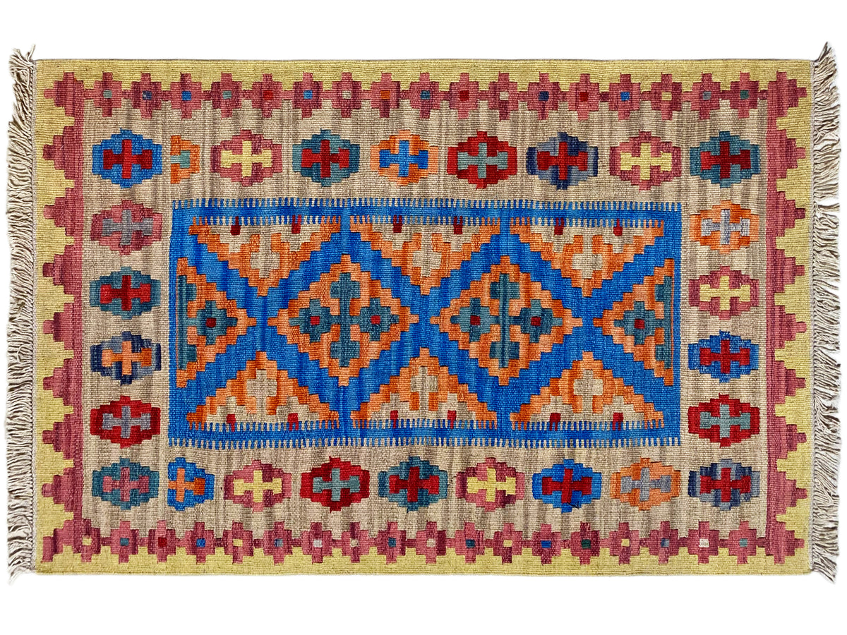 Kilim rug detail: beige background with blue central border, red-orange patterns, fringes