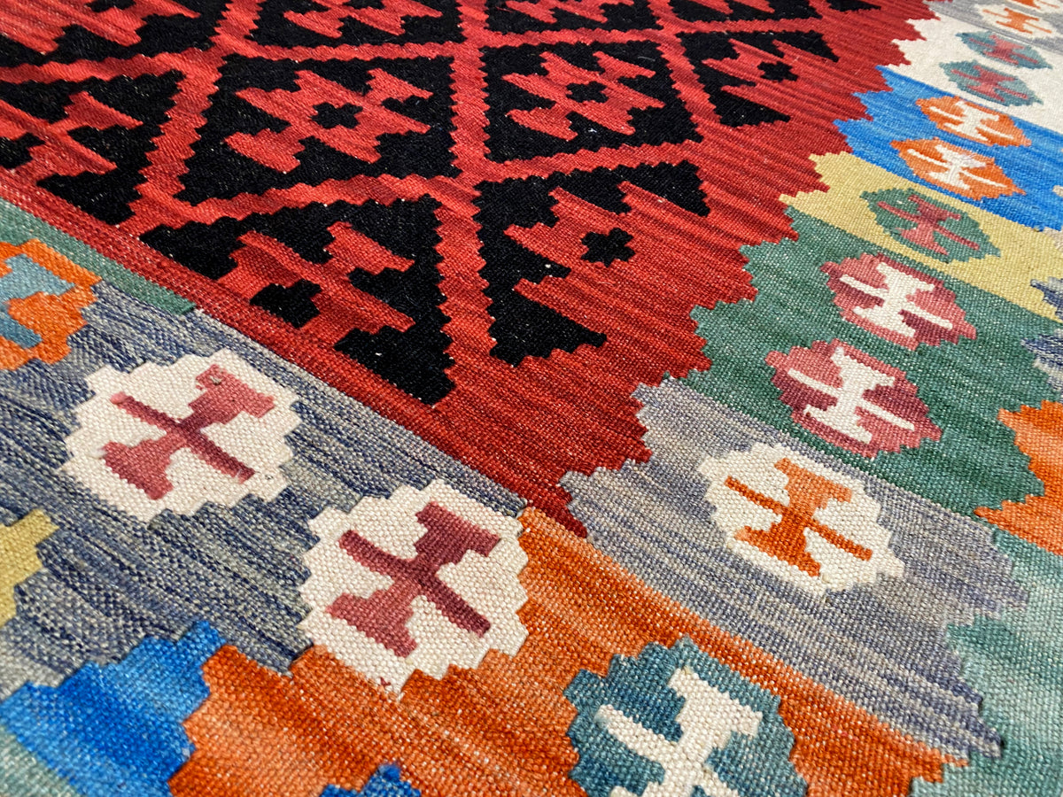 Kilim rug with a geometric pattern in red, black, and shades of blue and green