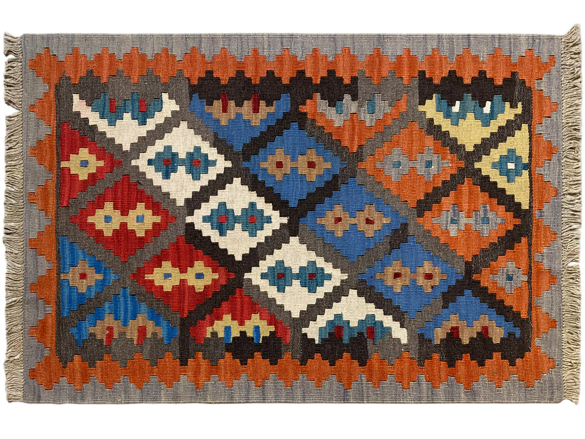 Rectangular kilim rug with colorful diamonds, gray base, orange fringes along the edges