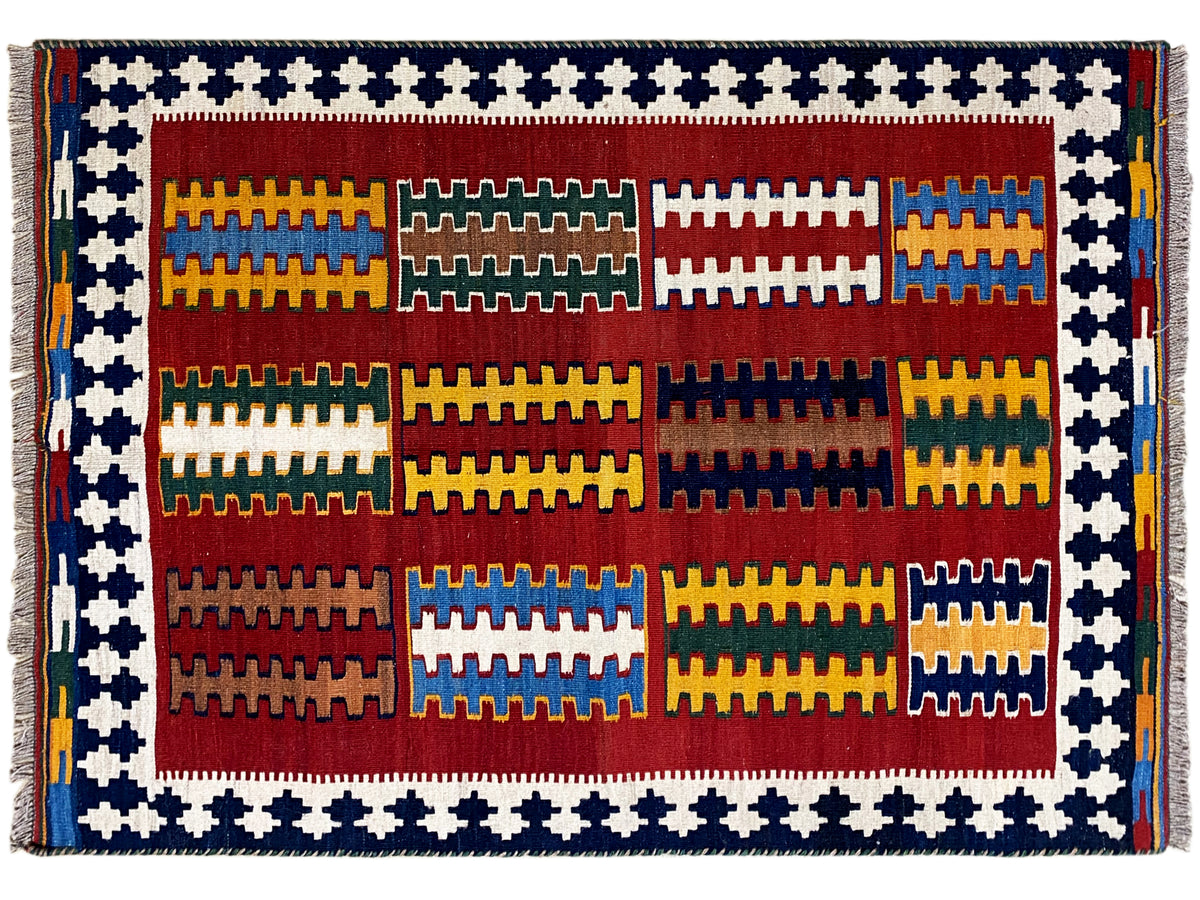 Kilim rug with a wide blue-and-white border, interior pattern of red, yellow, and green blocks