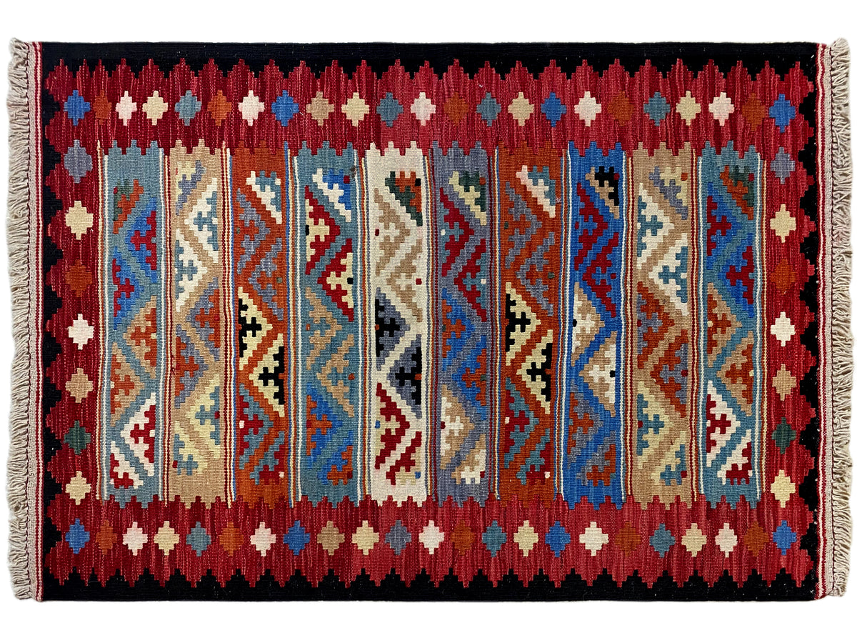 Rectangular kilim rug with central decorative bands and patterned stripes in red, blue, and beige.