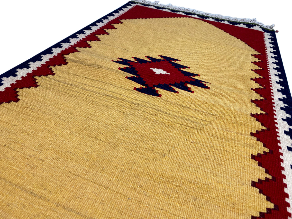 Yellow kilim rug with a red and blue pattern, edged with decorative trim