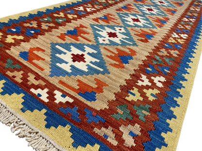Close-up of a kilim rug: cross and diamond patterns in blue, red, green, and cream