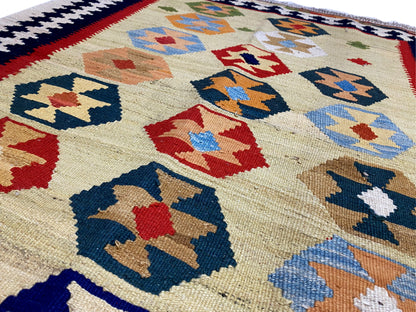 Kelim Qashqai rug in beige with detailed geometric motifs in blue, red, and green