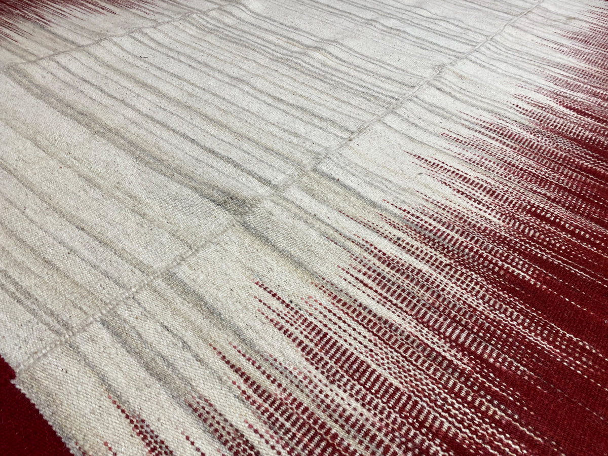 Kelim-Teppich-Detail: helle Flächen mit weinroten Linien und feinem Schimmer
