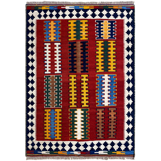 Kilim rug with a red central field, yellow and blue patterns, a blue-and-white zigzag border, and fringe