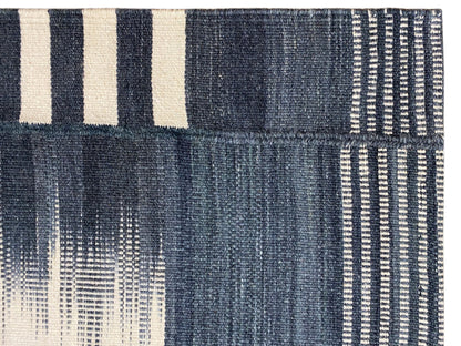 Close-up of a kilim rug: dark blue with white stripes and a woven texture