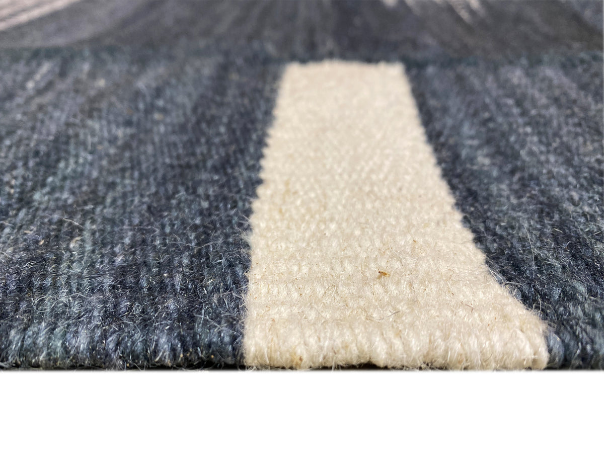 Kilim rug corner detail: dark blue with a beige triangle and woven edge