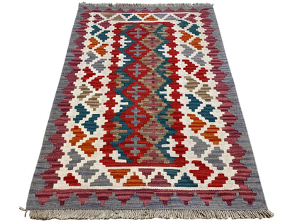 Rectangular kilim rug with a large geometric pattern in red, blue, green, and white