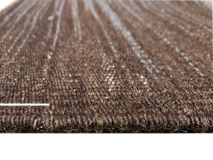 Teppichoberfläche im Detail: dichter Flor und hellgraue Linien auf dunkelbraunem Grund.