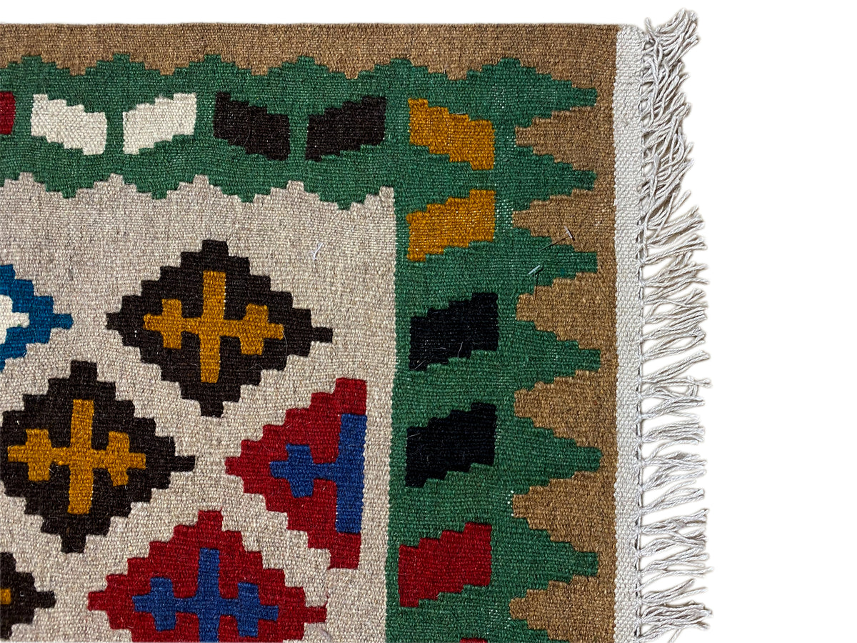 Kilim Qashqai rug, detail of the weave structure with fringes and green elements along the edge